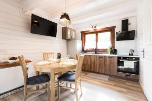 a kitchen and dining room with a wooden table and chairs at Domki Cicha Struga in Chocieszow +38 photos