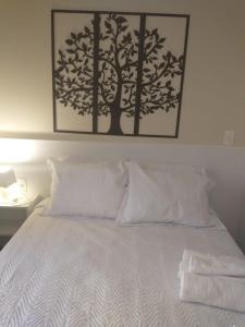 a bed with white pillows and a picture on the wall at Ap smart Campinas in Campinas