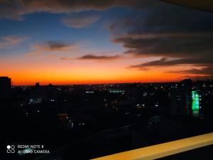 uma vista para o pôr-do-sol de uma cidade à noite em Ap smart Campinas em Campinas