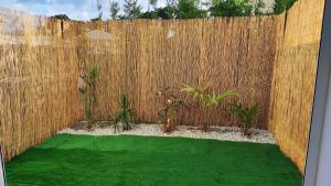 a backyard with a wooden fence and green grass at Studio confort avec jardinet in Montjoly