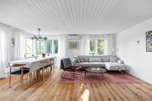 een witte woonkamer met een bank en een tafel bij Peaceful family home with indoor fireplace in Åkersberga