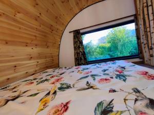 a bedroom with a bed with a floral bedspread and a window at Guitar House - Symphony Resort in Râşnov