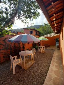 a table and chairs with an umbrella on a patio at SUÍTES ITABERABA BOIÇUCANGA in Boicucanga