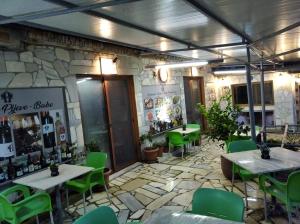 un restaurante con sillas y mesas verdes y una pared de piedra en Guest House Bake, en Gjirokastra