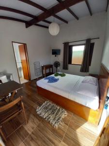 a bedroom with a bed and a table and a desk at SUÍTES ITABERABA BOIÇUCANGA in Boicucanga