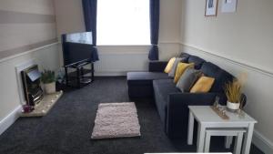 a living room with a blue couch and a tv at Hamble Lounge - Accomodation for Aylesbury Contractors & Industrial estate - Free Parking & WIFI Sleeps up to 6 people in Buckinghamshire