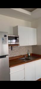 een witte keuken met een wastafel en een magnetron bij Mountain Beach View, Apartments in Sandhills Hellshire in Braeton