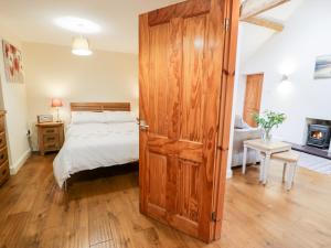 - une chambre avec un lit et une porte en bois dans l'établissement Ty Taid, à Gaerwen