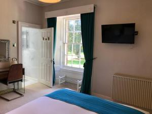 a bedroom with a bed and a television on the wall at Lunan House in Arbroath