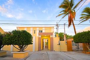 a yellow house with a yellow door and a palm tree at DT La Paz Condos with Pool & Palapa Lounge, 2 mi to Malecón in La Paz