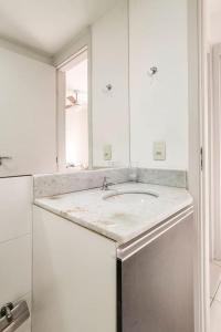 Baño blanco con lavabo y espejo en Apartamentot perfeito, aconchegante e com Clube, en Río de Janeiro