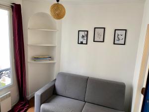 una sala de estar con sofá y algunas fotos en la pared en Home Sweet Home Montmartre Duperre en París