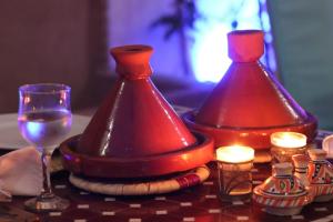 dos jarrones rojos sentados en una mesa con una copa de vino en Riad Dar Mamouni, en Marrakech