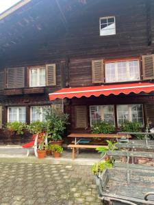 un edificio con un banco y un toldo rojo en Uncle Eric's Chalet en Matten