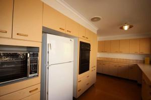 a white refrigerator in a kitchen with wooden cabinets at Hearthstone in Blackheath