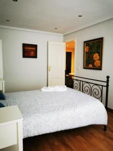 1 dormitorio con 1 cama grande con manta blanca en Apartamento en el centro de OVIEDO, en Oviedo