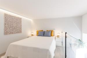 a white bedroom with a white bed with yellow pillows at FLH Beato Lofts in Lisbon