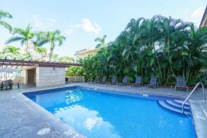 a large swimming pool with chairs and palm trees at Studio Unit at the Royal Garden, in Waikiki ワイキキ・ロイヤルガーデン in Honolulu