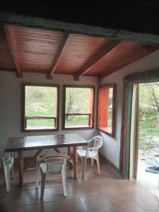 a table and chairs in a room with windows at La Protegida in El Chalten