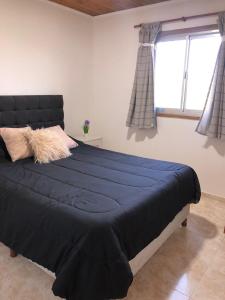 a bedroom with a large bed with blue sheets and a window at CABAÑAS FENIX con ARROYO NATURAL BORDEANDO LA PROPIEDAD reservar con 24 hs de anticipación in Villa Amancay