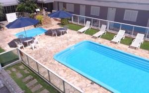 uma piscina com cadeiras, uma mesa e guarda-sóis em Hotel Pousada Ilha do Mar Bombinhas em Bombinhas