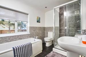 a bathroom with a tub and a toilet and a sink at Spacious house, private garden, parking & Netflix in Derby