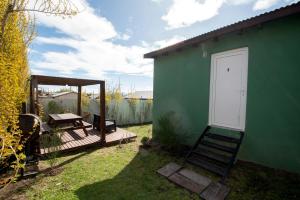 a green house with a porch and a white door at Complejo de cabañas Atrapasueños in El Calafate
