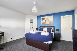 a bedroom with a large bed with blue walls at Spacious house, private garden, parking & Netflix in Derby