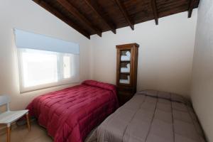 um quarto com uma cama vermelha e uma janela em Complejo de cabañas Atrapasueños em El Calafate