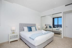 a white bedroom with a large bed and a mirror at Sub Penthouse Oracle 46th floor - GC Getaways in Gold Coast