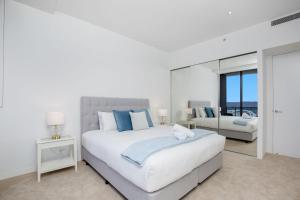 una camera da letto bianca con un letto grande e uno specchio di Sub Penthouse Oracle 46th floor - GC Getaways a Gold Coast Altre 37 foto