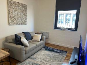 sala de estar con sofá y ventana en The Dereham - Open Plan Apartment 1 min from the city centre, en Leicester