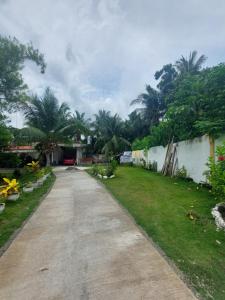 a driveway leading to a yard with palm trees at Maui's Place in Badian