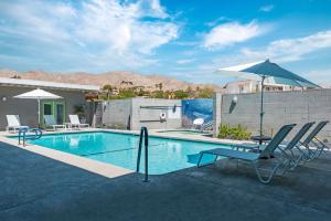 - une piscine avec des chaises et un parasol dans l'établissement Desert Hot Springs Inn, à Desert Hot Springs