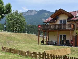 Chalet in Koetschach-Mauthen ski area في كوتسخاخ: منزل على تلة مع سياج خشبي