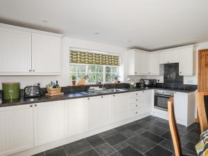 a kitchen with white cabinets and a window at Cennin in Criccieth