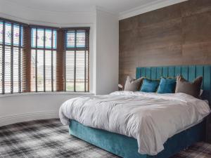 a bedroom with a blue bed and two windows at Hampton House in Blackpool