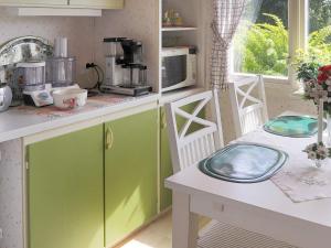 a kitchen with green cabinets and a table with a microwave at 4 person holiday home in Åskloster-By Traum in Åskloster