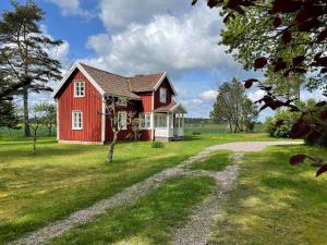 a red house on a green field with a dirt road at Holiday home GRÄSTORP in Grästorp