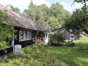 uma velha casa preta com um jardim de relva em Holiday home SIMLÅNGSDALEN IV em Simlångsdalen