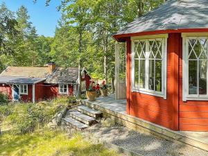 czerwony domek z tarasem na dziedzińcu w obiekcie Holiday home öRSJö II w mieście Örsjö