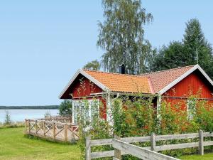 een rode schuur met een hek ervoor bij Holiday home HJO III in Hjo