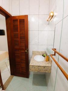 a bathroom with a sink and a wooden door at Pousada Aquarela do Mar in Abraão