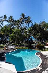 une piscine avec des palmiers en arrière-plan dans l'établissement Beaches Holiday Apartments with Onsite Reception & Check In, à Port Douglas