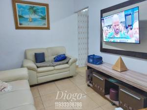 salon z kanapą i telewizorem z płaskim ekranem w obiekcie Casa Praia Grande WIFI 2dorm 2ban 2carr churrasq 400mts da praia Tupi w mieście Praia Grande