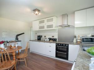 Southleigh的住宿－Purlbridge Bungalow，厨房配有白色橱柜、木桌和用餐室