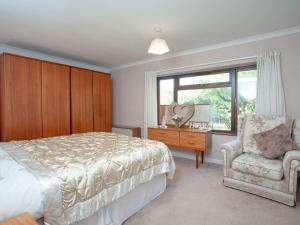 a bedroom with a bed and a chair and a window at Purlbridge Bungalow in Southleigh