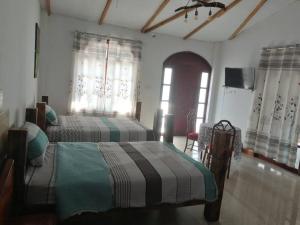 1 dormitorio con 2 camas, TV y ventanas en Casa de campo en contacto con la naturaleza., en Tingo María