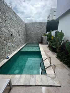 una piscina junto a una pared de piedra en Flat 313 Bauten Cabo Branco, en João Pessoa