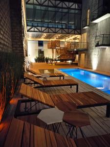 una piscina con tavoli e sedie in legno accanto a un edificio di Hotel Tila a Cholula